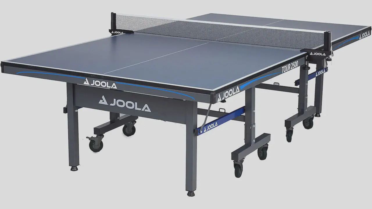 Featured image of the JOOLA Tour 2500 indoor Table Tennis Table, highlighting its independent table halves with stable foldable steel legs, a dark blue 1-inch tabletop with UV-cured silk striping, and locking caster wheels for professional-grade play.
